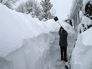 Man shoveling a path through 6 feet of snow.
