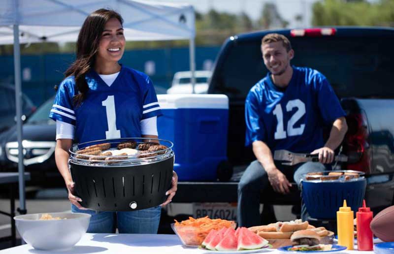 Woman carrying a grill while tailgating.